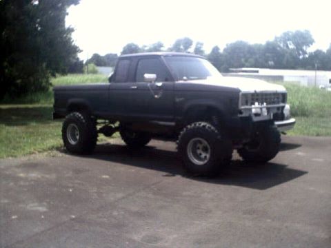 1996 Ford Bronco - A modified pickup truck with a lifted suspension and oversized tires sits on a paved surface outdoors.