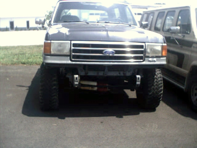 Front view of lifted dark gray truck with winch, next to another vehicle
