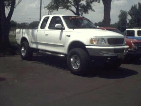 1996 Ford Bronco - White 1997 Ford F-150 pickup truck seen from the front-right angle.