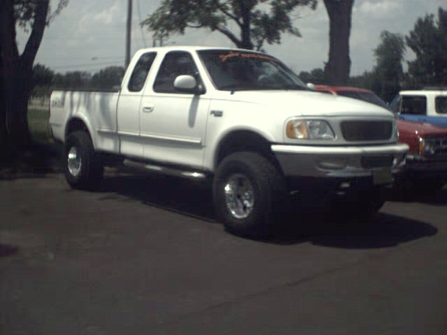 White Ford F-150 pickup truck, 1997 model year, parked outdoors. Another vehicle is partially visible to the right