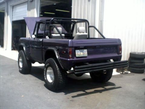 1996 Ford Bronco - This modified Ford Bronco features a roll cage and custom rear bumper, with its hood up in front of a garage.