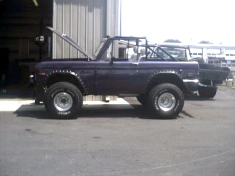 1996 Ford Bronco - Side view of a purple Ford Bronco, hood up, with a second vehicle behind it.