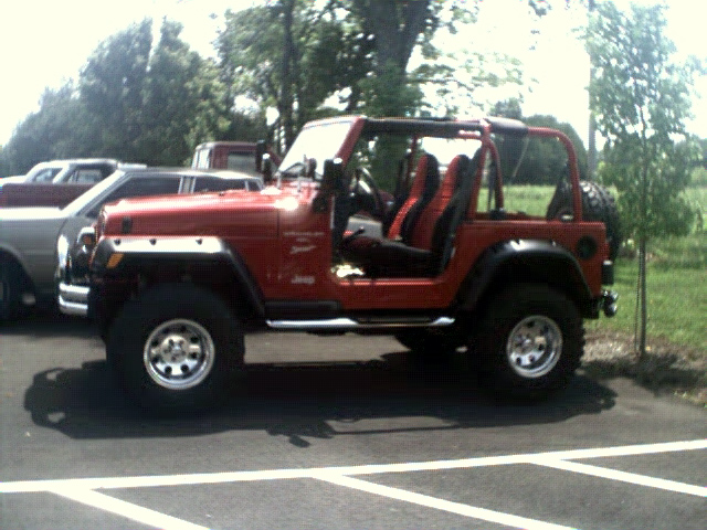 Red Jeep Wrangler with black interior, side view, parked on asphalt