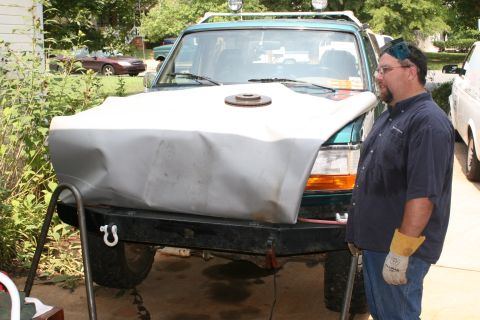 1996 Ford Bronco - A man stands by a green Ford Bronco, which has a custom bumper and a tarp covering its hood.