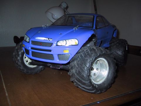 1990 Ford Bronco - Blue RC monster truck with oversized tires is displayed indoors.