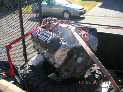 1996 Ford Bronco - A Ford Racing engine is secured with straps in a trailer, with a car visible in the background.