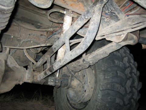 1994 Ford Bronco - Underside view of a vehicle's rear axle and suspension system, showing leaf springs and a shock absorber.