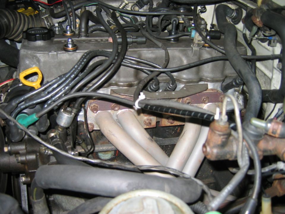 Ceramic-coated four-cylinder tubular exhaust header installed in an engine bay