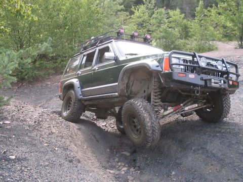 1992 Ford Bronco - This modified Jeep Cherokee XJ navigates a steep, rocky incline on a wooded trail.