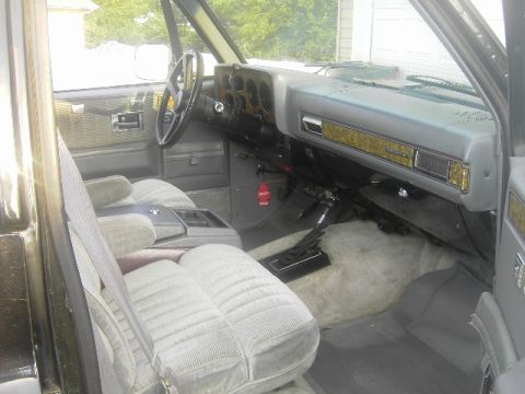 1990 Chevrolet Suburban - The interior of the vehicle features cloth seats, wood grain trim on the dashboard, and a floor-mounted gear shifter.
