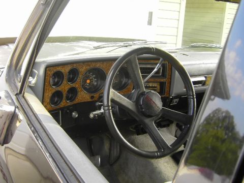 1990 Chevrolet Suburban - The interior of a classic Chevrolet truck shows its dashboard with woodgrain accents and a prominent steering wheel.