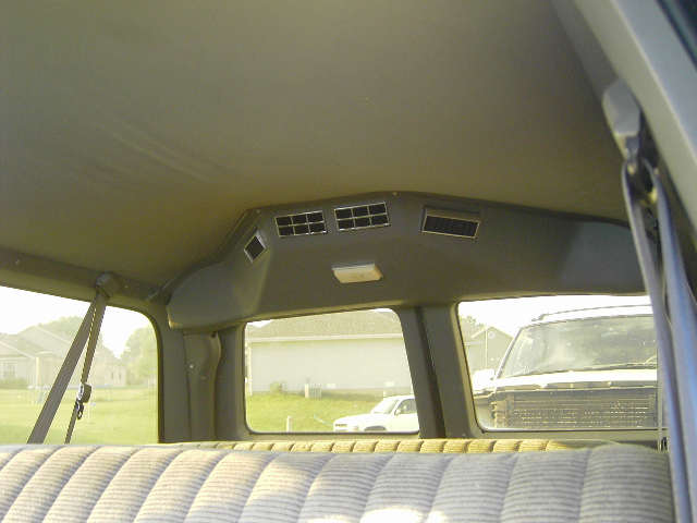 Interior view looking out rear window at another SUV and a house