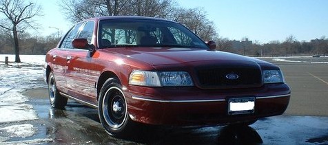 1999 Ford Crown Victoria - This Ford Crown Victoria has a dark grille and chrome trim around the headlights.