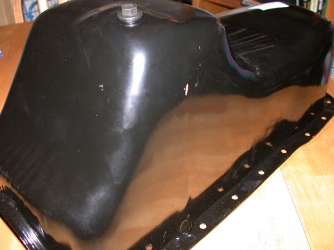 1995 Ford Bronco - A close-up view of a vehicle's oil pan, showing its metallic surface and bolt attachment.