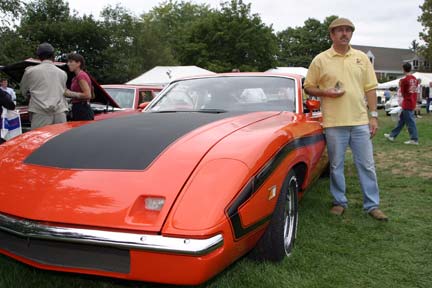 1970 Ford Ranchero - Man stands next to a bright orange 1970 Ford Ranchero at an outdoor car show.