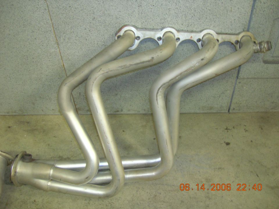 Exhaust manifold with four pipes merging into two, mounted on a wall