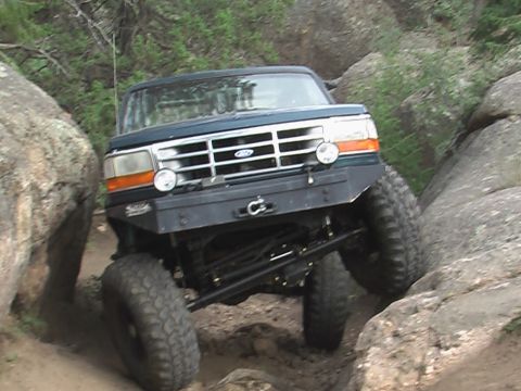 1981 Ford Bronco - This modified SUV navigates a challenging rocky trail, its grille suggesting a 1992-1997 model year.
