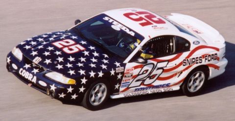 1995 Ford Mustang - A 1995 Ford Mustang race car, adorned with stars and stripes, speeds around a track.