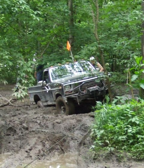 1985 Ford F-150 - Pickup truck struggling through deep mud on an off-road trail.