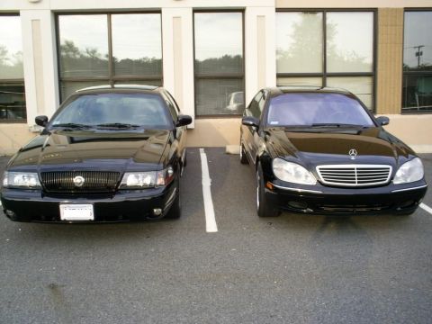 2003 Mercury Marauder - A black 2003 Mercury Marauder is parked in front of a building, alongside another black sedan.