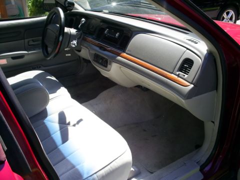 1995 Ford Crown Victoria - The interior of a 1995 Ford Crown Victoria shows light grey cloth seats and a dashboard with wood trim accents.