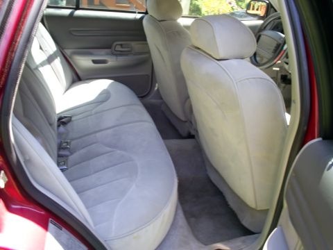 1995 Ford Crown Victoria - The interior of a red sedan features light gray cloth seats and a view of the dashboard and steering wheel.