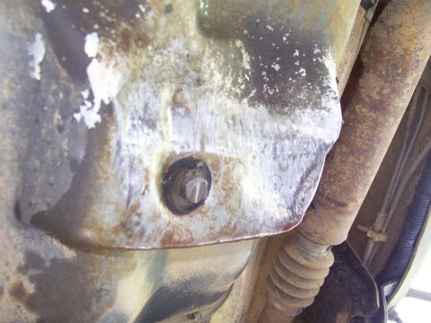 1992 Ford Bronco - Close-up view of the oil pan drain plug and surrounding undercarriage components.