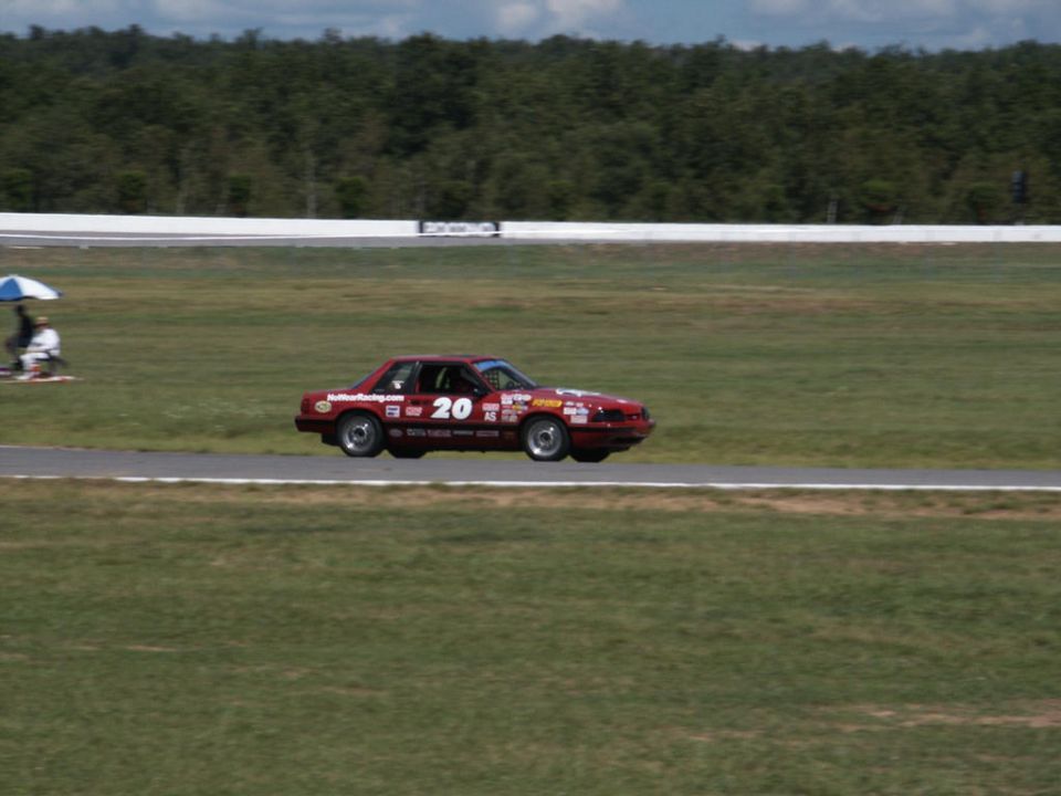 red race car with number 20 and many stickers on a track