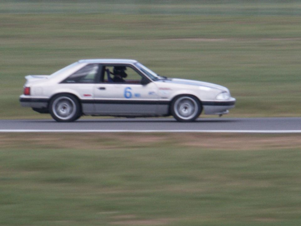 White coupe race car with number 6 on door, side view, on a track