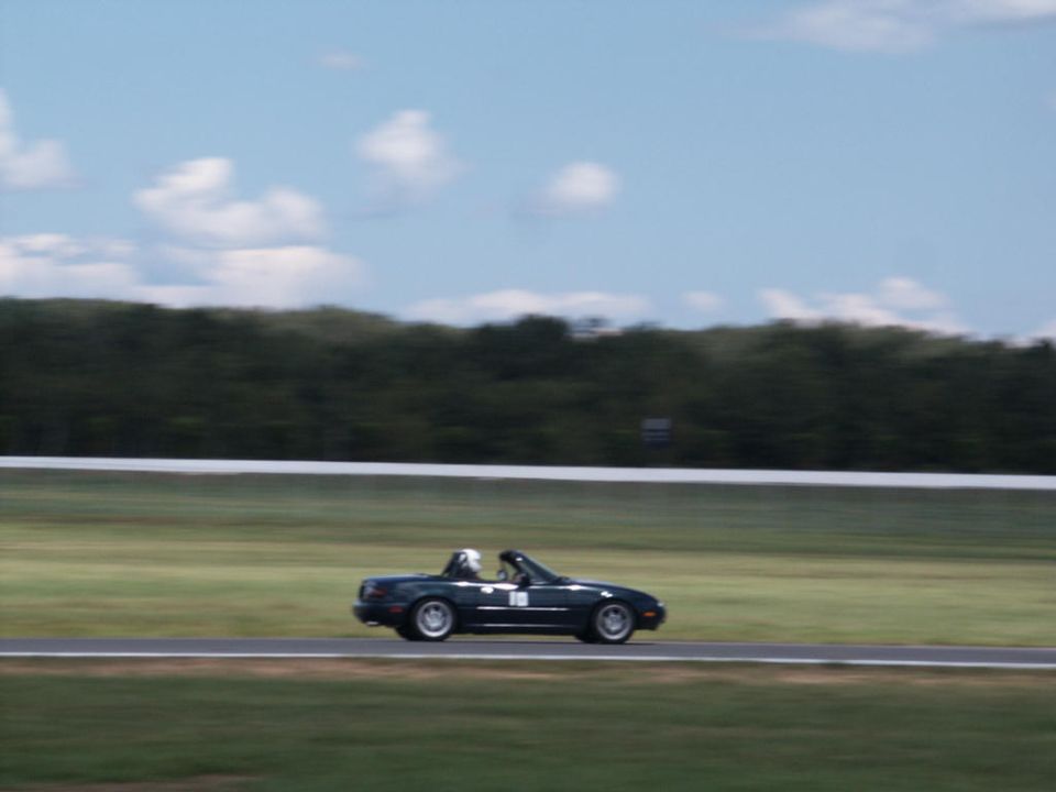 dark convertible sports car with a driver on a race track, blurred background