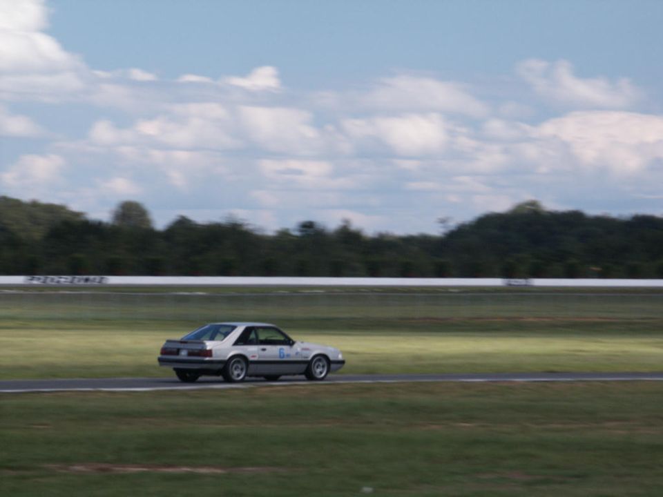 Silver Ford Mustang on a racetrack, number 6 on the door