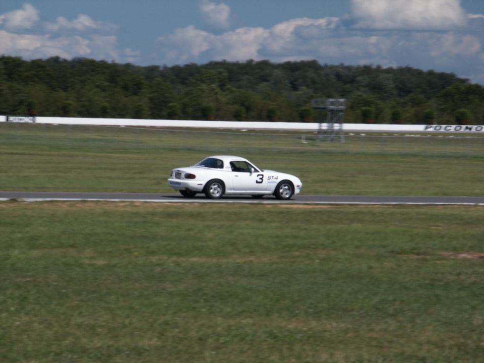 White Mazda Miata with number 3 on side, driving on a race track