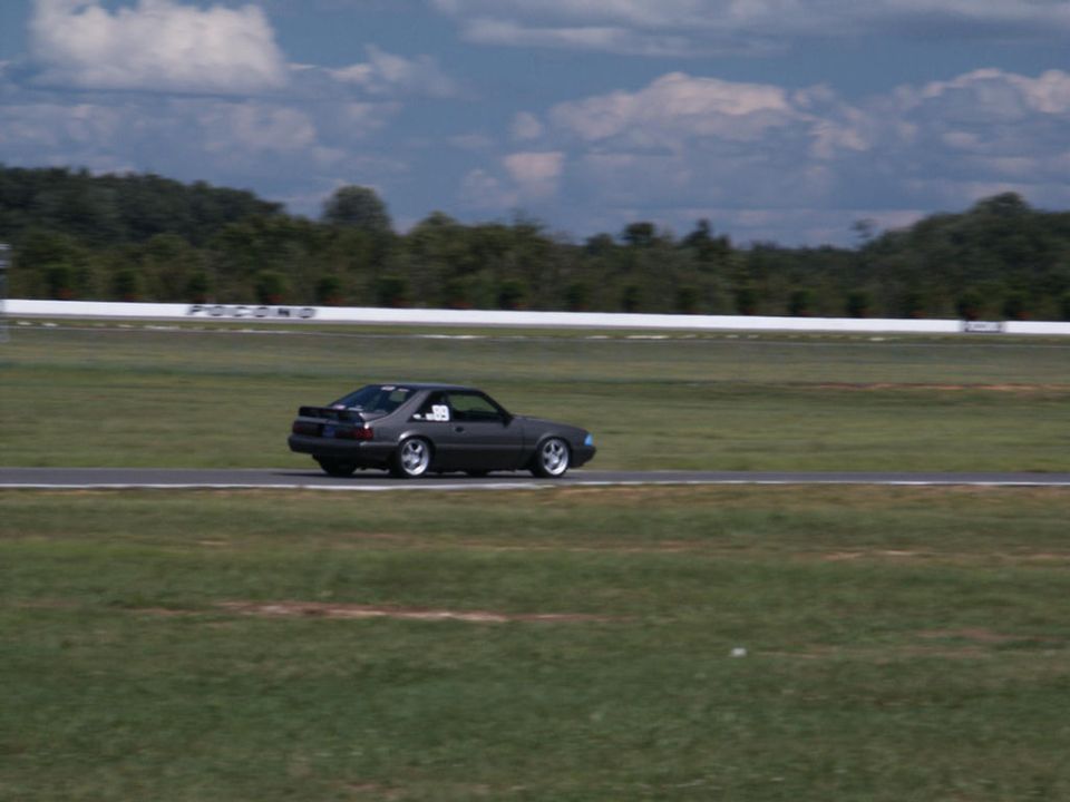 Dark gray coupe with a rear spoiler on a racetrack, side view