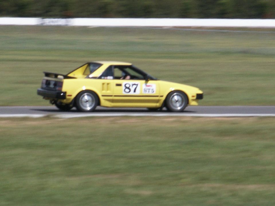 Yellow sports car with number 87 and STS decals on the side, on a race track