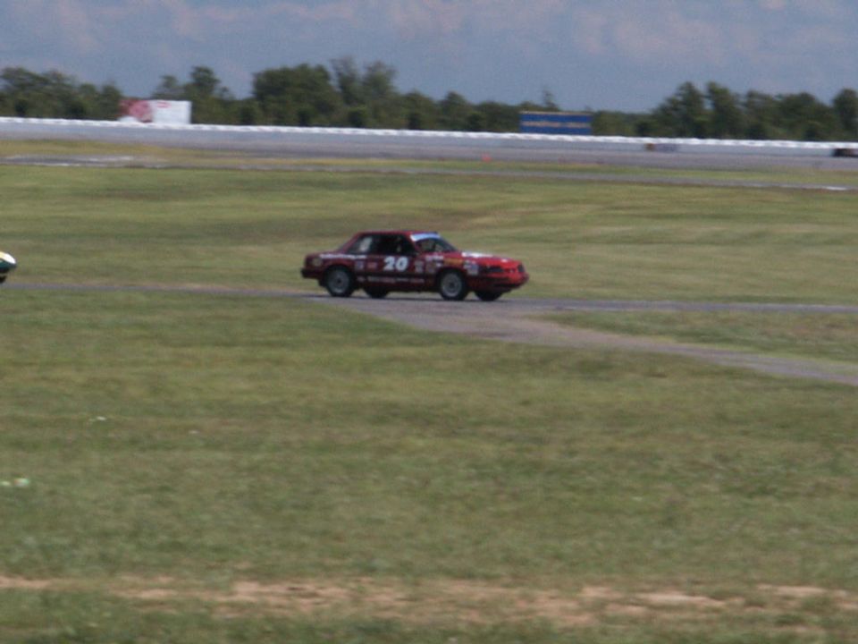 Red race car with number 20 on the side, driving on a track