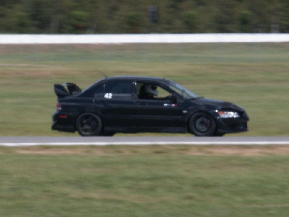Black sedan with racing number 42 on the door, large rear spoiler, on a race track