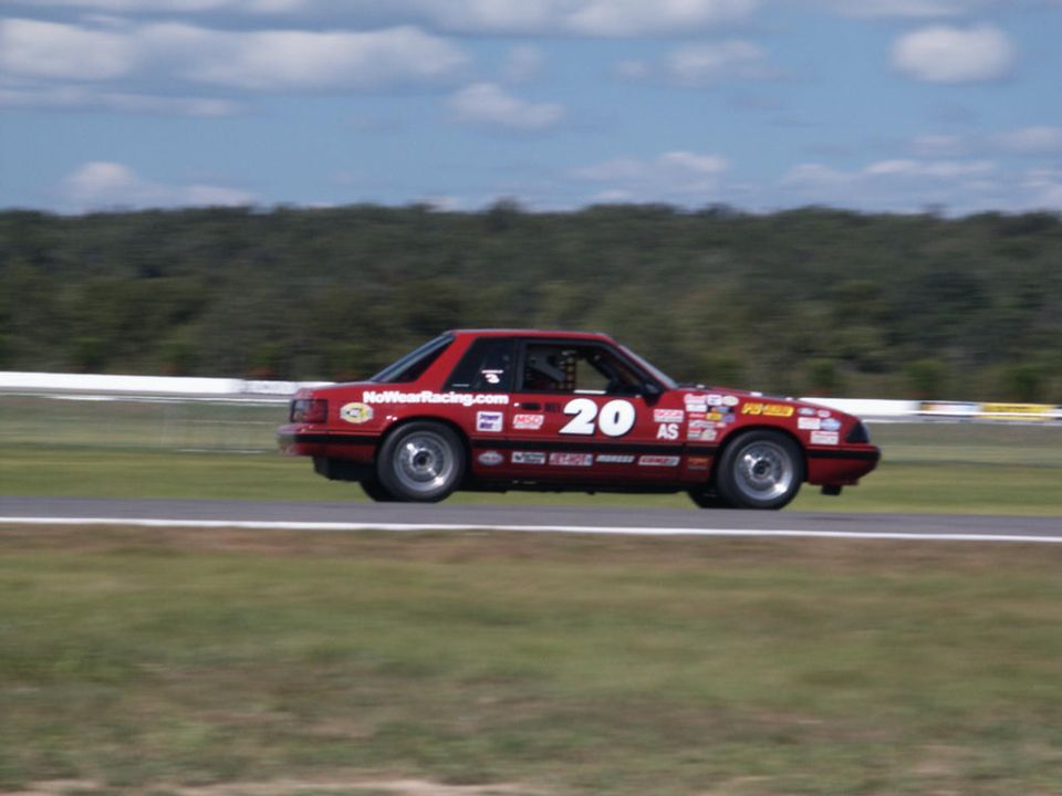 Red Fox-body Mustang number 20 road race car cornering on a road course