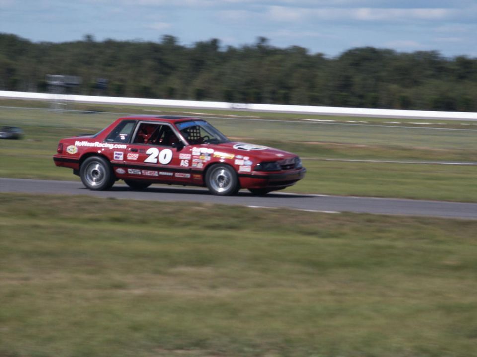 Red race car with number 20 and various sponsor decals on a track