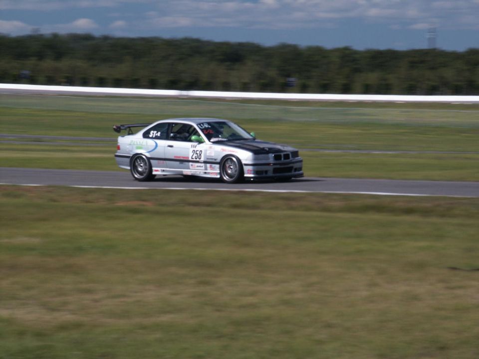 Silver BMW M3 race car with black hood and spoiler on a track, number 258 visible