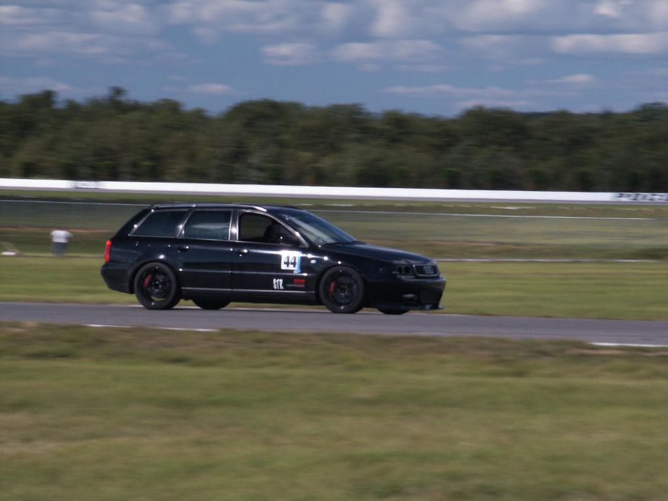 Black Audi station wagon with racing numbers on the door drives on a track