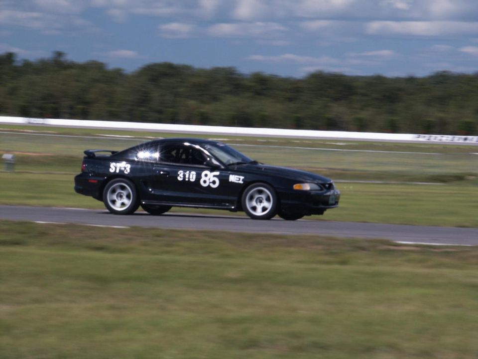 Black Ford Mustang with racing numbers 310 85 on side, on a race track
