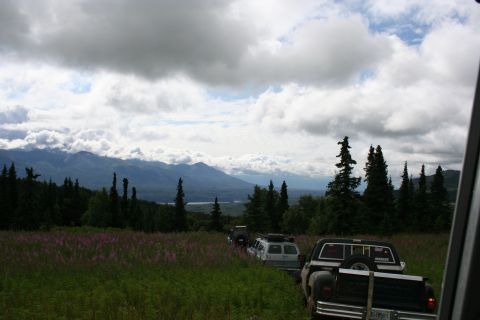 2004 Jeep TJ - Several off-road vehicles are parked in a field with mountains in the distance.