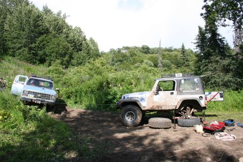 2004 Jeep TJ - Two off-road vehicles, a Jeep TJ and a Chevrolet van, are on a dirt path surrounded by dense foliage.