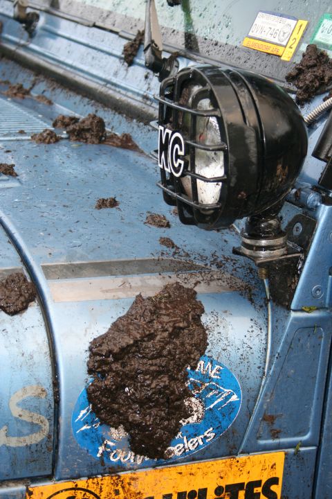 2004 Jeep TJ - This off-road vehicle is covered in mud, with a KC light and stickers visible on its exterior.