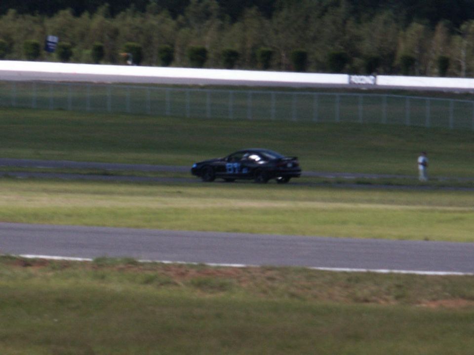 Black 2001 Mercury Grand Marquis with blue racing numbers on the door, seen from the side on a race track