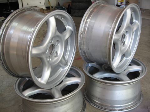 1994 Ford Probe - A set of four silver alloy wheels, each a five-spoke design, are stacked and displayed.