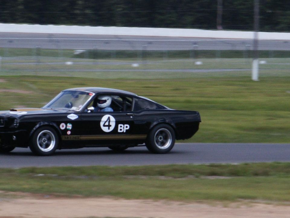 Black 1967 Shelby GT500 on a race track, number 4 and BP decals visible