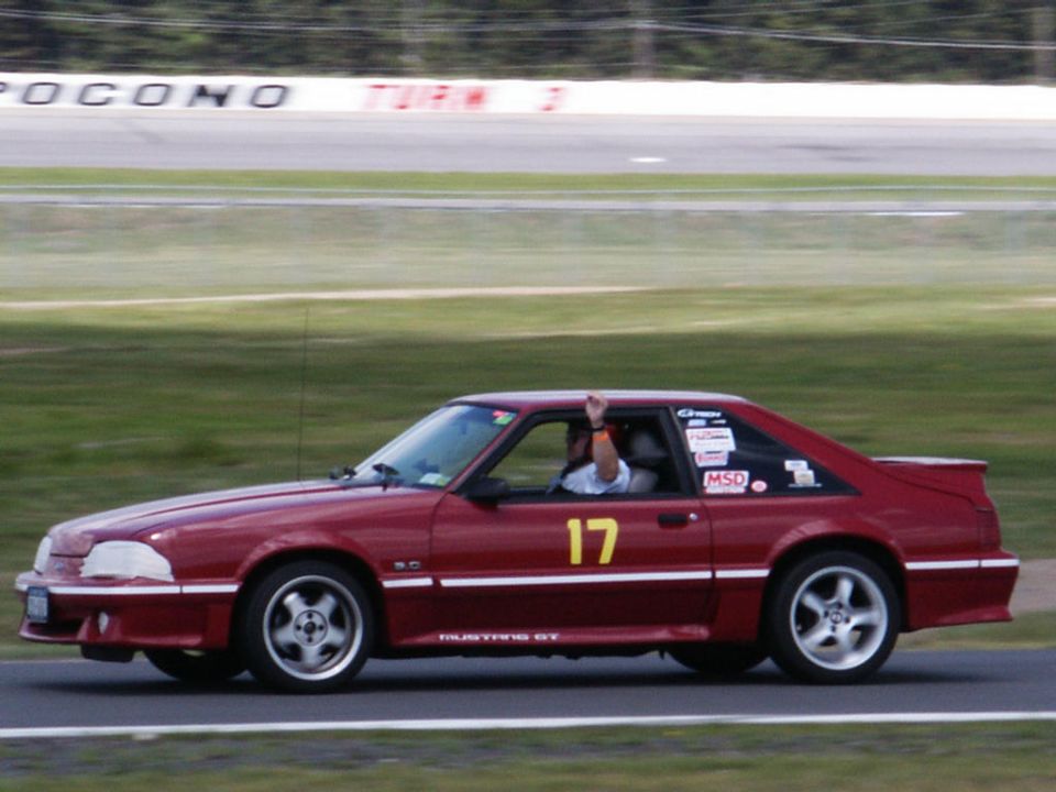 Red Ford Mustang GT with number 17 on door, driving on a race track