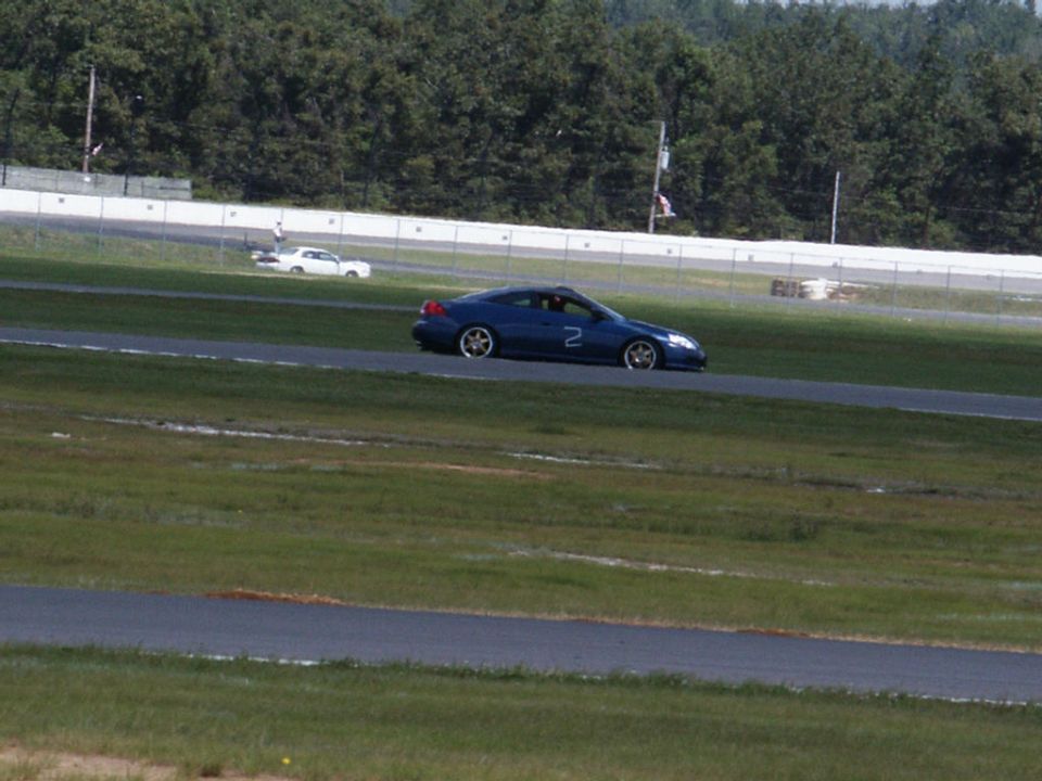 Blue coupe with number 2 on door on race track, white car in background