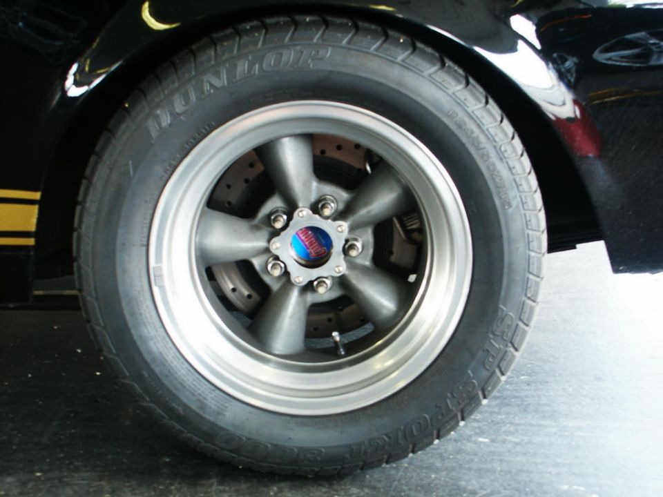 Close-up of a five-spoke wheel with a yellow stripe on a black car
